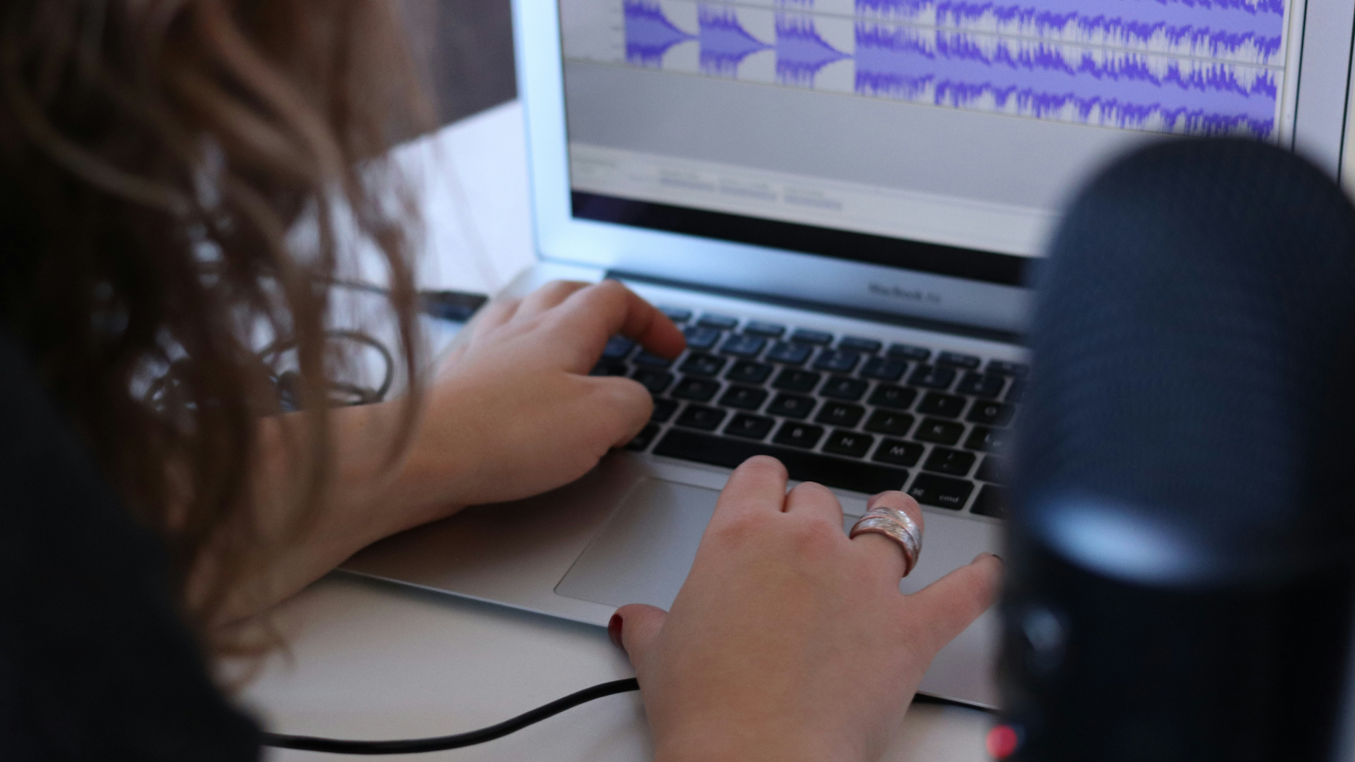 person editing audio on a laptop for audible content