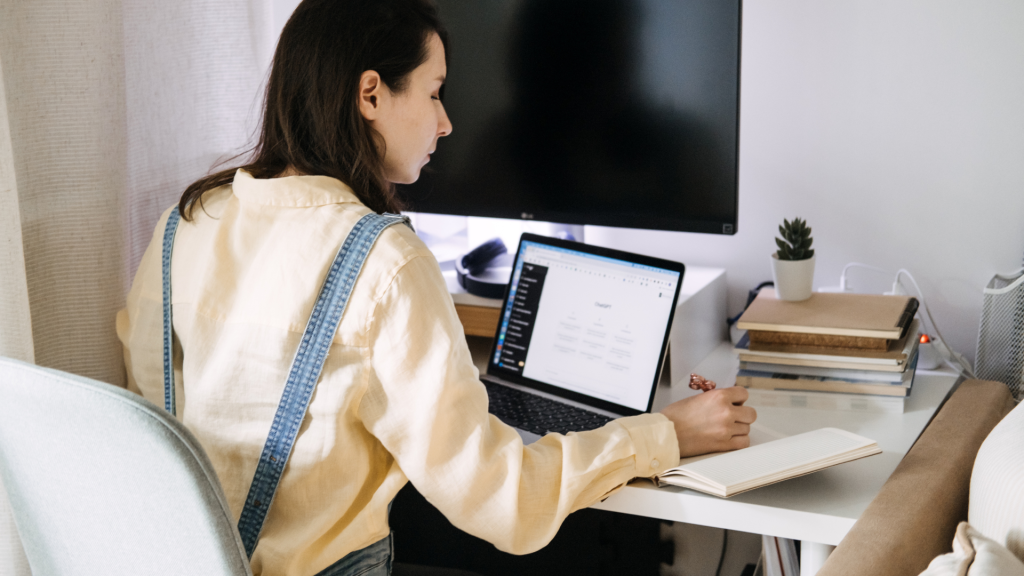 woman using chatgpt on a laptop while taking notes on passive income ideas